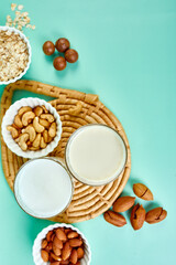 Various vegan plant based milk and ingredients, non-dairy milk, alternative types of vegan milks in glasses on a blue background , flat lay, top view with copy space