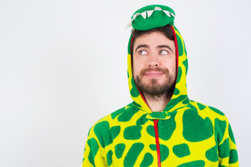 Young caucasian man wearing a pajama standing against white background looking aside into empty space thoughtful
