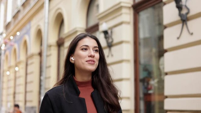 Beautiful woman using smartphone and wireless handsfree for audio call walking on the street. Closeup portrait smiling lady talking mobile phone with colleagues, relatives and friends