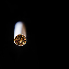 The tip of an unlit cigarette on a black background. Cannabinoids, tobacco, marijuana, and other...