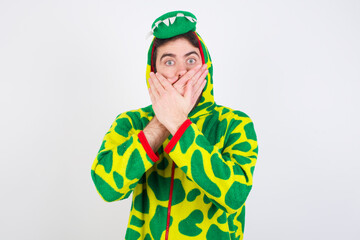 Young caucasian man wearing a pajama standing against white background shocked covering mouth with hands for mistake. Secret concept.