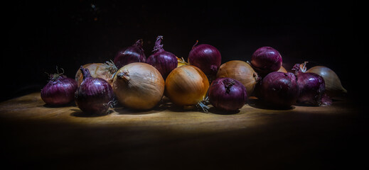 Vegetable concept. Onions in dark on wooden table. Selective focus