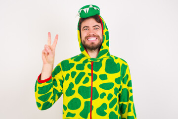 Fototapeta premium Young caucasian man wearing a pajama standing against white background showing and pointing up with fingers number two while smiling confident and happy.