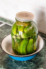 A large glass jar full of lightly salted cucumbers