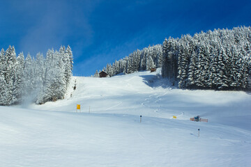 The 'Kleinberg' ski slope in wintertime with active snow cannon and fair weather in Filzmoos...