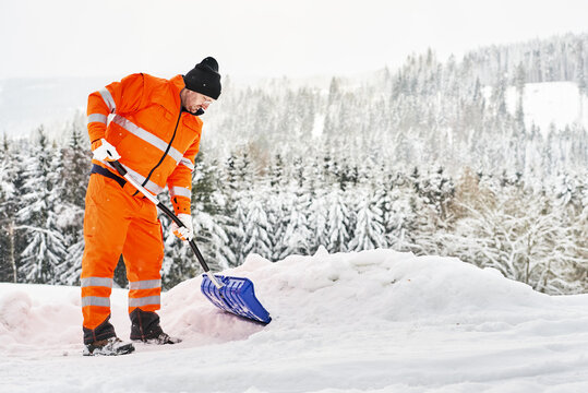Kommunaler Service Arbeiter in oranger Sicherheitsuniform reinigt Wege und Straßen nach Schneefall