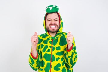 Fototapeta premium Young caucasian man wearing a pajama standing against white background being excited for success with raised arms and closed eyes celebrating victory. Winner concept.
