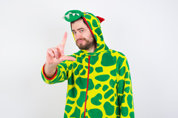Fototapeta premium Young caucasian man wearing a pajama standing against white background making fun of people with fingers on forehead doing loser gesture mocking and insulting.
