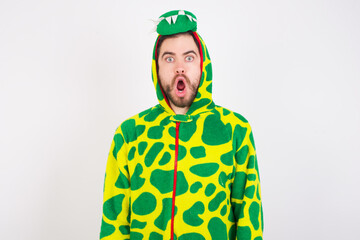 Oh my God. Surprised Young caucasian man wearing a pajama standing against white background stares at camera with shocked expression exclaims with unexpectedness,