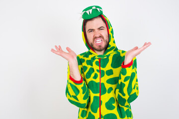 Indignant Young caucasian man wearing a pajama standing against white background gestures in bewilderment, frowns face with dissatisfaction.