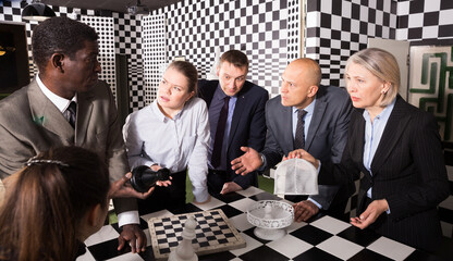 Men and women in business suits solving puzzles with chess to get out of escape room