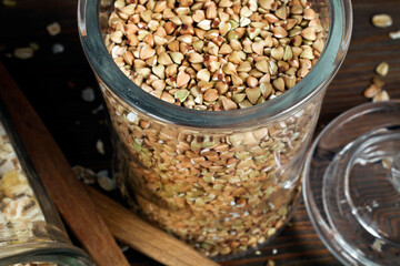 Glass jars of green buckwheat on a wooden background. Top view.