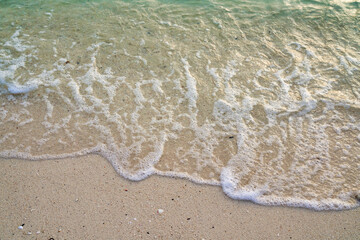 Surface of sea wave bubbles on sand beach for background