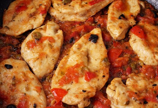 Fettine di petto di pollo alla siciliana con pomodoro, olive nere, capperi, origano e aglio.