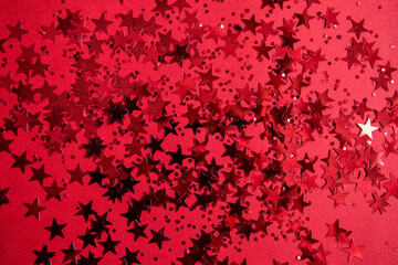 Red confetti in the form of stars on a red background