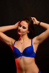 Fototapeta premium Portrait of brunette girl in underwear standing in the studio with black background.