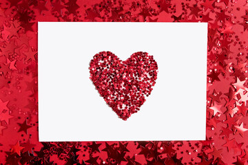 White rectangular paper with a heart in the middle on a red background with confetti in the form of stars.