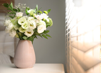 Bouquet of beautiful flowers on nightstand in bedroom, space for text. Interior design