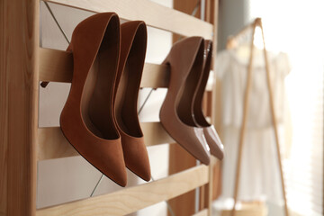 Rack with stylish women's high heeled shoes in dressing room. Modern interior design