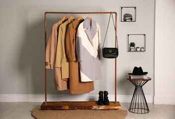 Different warm coats on rack in stylish room interior - obrazy, fototapety, plakaty