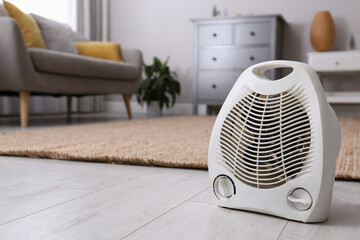 Modern electric fan heater on floor at home. Space for text © New Africa