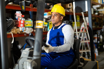 Portrait of confident hispanic worker driving forklift in building materials store