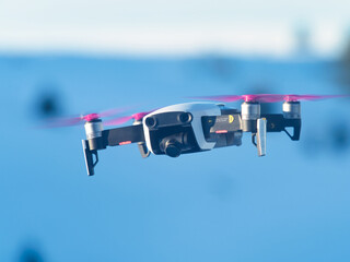 Fototapeta premium A drone with camera during the flight while filming and behind the blue sky
