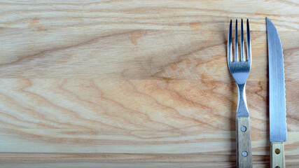 fork and knife on the right on light beech board, top view, ad banner concept, place for text, Images with Copy Space