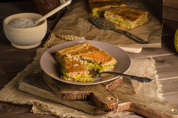 Sliced piece of pie with cabbage on a wooden background in a rustic style