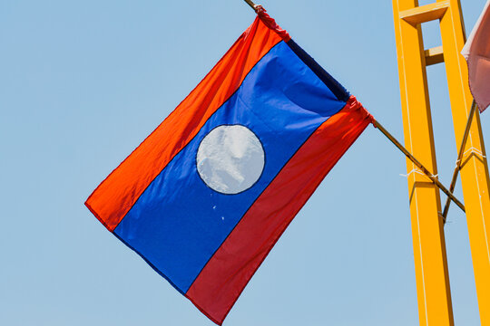 Low angle shot the flag of Laos against a light blue sky