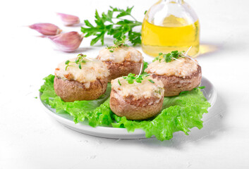 Stuffed champignons with cheese and garlic and roasted in the oven. Hot appetizer served on the white table