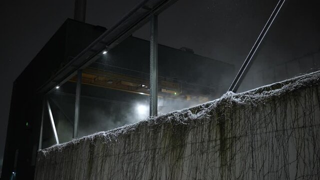 Automatic industrial grab crane working during cold night while it's snowing and steam coming off material clamshell grab bucket