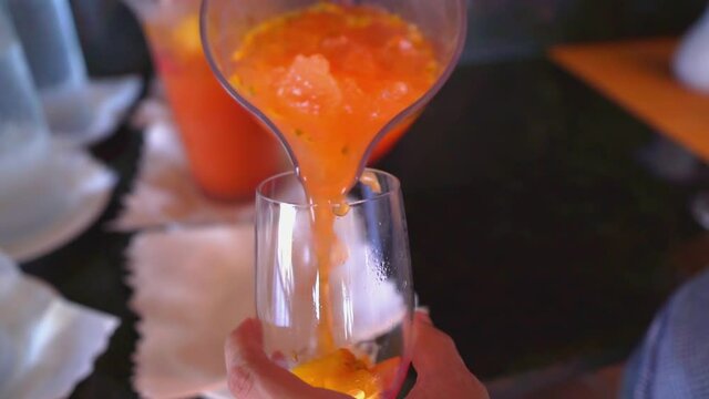 Pouring passion fruit or maracuja juice into glass. Slow-motion