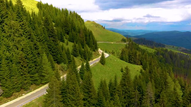 Motorcyclist driving his motorbike on the mountain forest road in the country side. A young man riding a motorbike on a countryside road. Motorbike driving along the wild mountain forest road. Aerials
