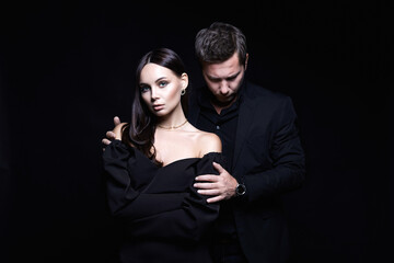 beautiful woman in evening dress in the hands of man in a suit. Couple over black background