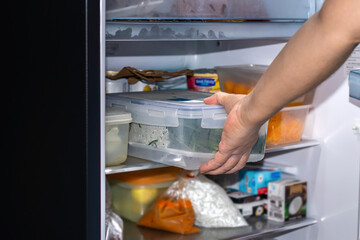 Hand of a young woman is opening a refrigerator door,closeup,Space for text