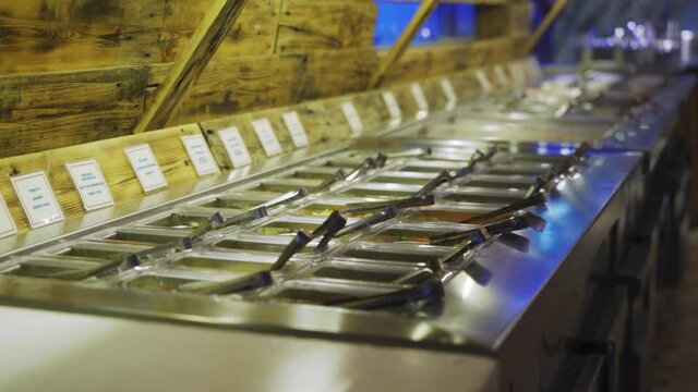 Long Buffet Table With Selection Of Vegetables And Meat With Tongs and Labels At A Korean Restaurant. - panning
