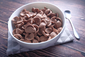 Close up of chocolate corn flakes in a bowl on wooden table 