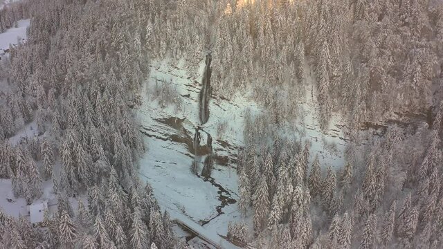 A Backward Travelling Aerial view of the Cascade du Rouget during winter covered in snow, French Alps.