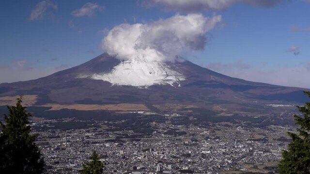 Locked off view over Gotemba city at bottom of snowy Mount Fuji on clear day