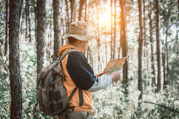 Asian male holding map for check location adventure in forest,  Holidays concept
