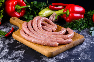 Fresh raw sausage on wooden board, Raw barbecue sausages with spices and vegetables. Top view Freshly made raw breed butchers sausages. Free space