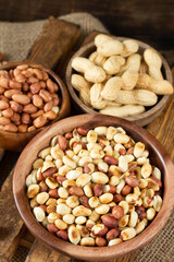 Roasted, raw peanuts and shelled in wooden bowls on a brown wooden table