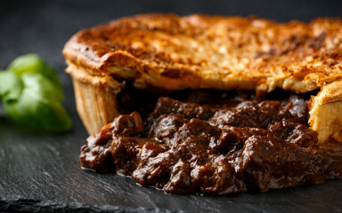 British beef steak pie with onion, wine gravy on rustic stone board