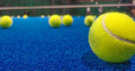Padel ball on the blue synthetic court on blurried background