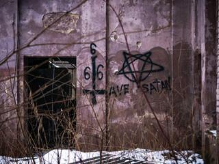 The interior space of a destroyed building with signs and inscriptions left by Satanists