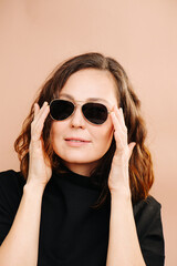 Portrait of a brunette in dark glasses on a beige background. High quality photo