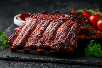 Grilled pork ribs with bbq sauce and herbs on stone board