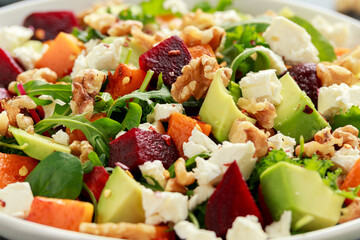 Healthy Butternut squash salad with beetroot, avocado, walnut and feta cheese in white bowl