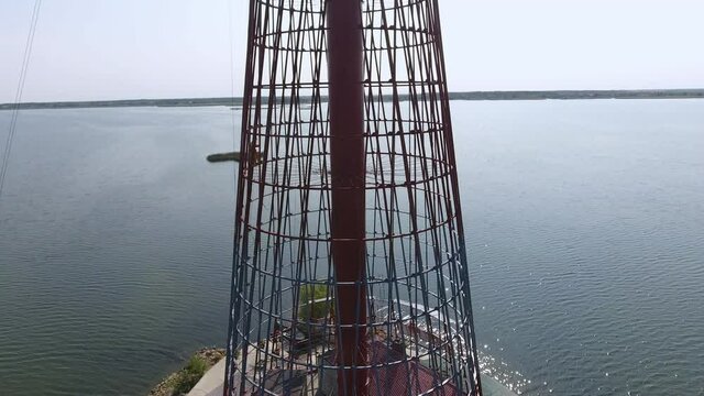 Aerial of lighthouse placed on small island with trees and houses in open sea 